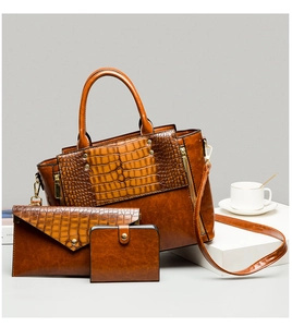Détail d'un ensemble cabas gaufré crocodile marron, pochette enveloppe et portefeuille à pression