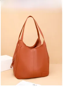 Close-up of burnt orange pebbled leather tote bag with elegant slender shoulder straps