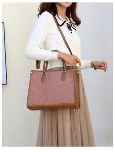 Detail of a brown crocodile embossed tote bag worn by a model in a minimalist setting