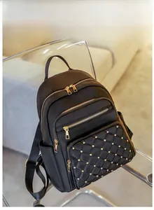 Detail of black oxford backpack featuring quilted diamond pattern and gold stud accents