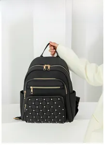 Detail of black quilted nylon backpack with gold studs and premium metal hardware