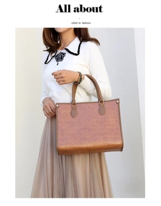 Detail of brown crocodile pattern tote bag with dual handles and textured leather surface