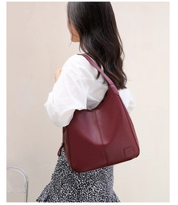 Detail of burgundy leather tote bag showing lychee grain texture and leather logo patch