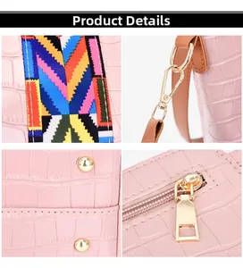Close-up of pink crocodile texture handbag with colorful strap and gold metal hardware