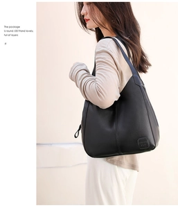 Shoulder shot of a black pebbled leather tote bag with embossed detail on a female model