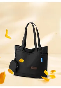 Detail of black canvas tote bag with outer pocket and detachable round pouch charm