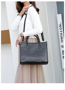 Detail of black crocodile texture tote bag with reinforced handles and shoulder strap