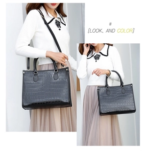Detail of black faux leather tote bag with crocodile pattern and adjustable strap