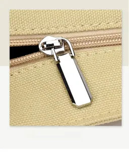 Macro shot of smooth silver metal zipper on premium cream canvas shoulder bag texture