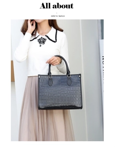 Close-up of black crocodile pattern faux leather tote bag held by a model in casual wear