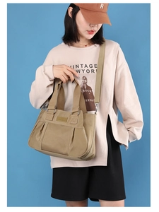 Large khaki nylon tote bag with pleated detail shown on a model against blue background