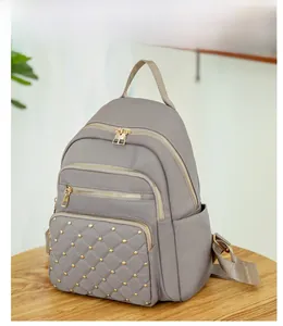 Detail of grey oxford backpack featuring diamond quilting and gold metallic rivets