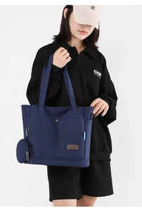 Detail of navy blue canvas tote bag featuring side pockets and a round coin purse attachment
