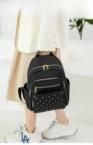 Detail view of quilted black nylon backpack with gold rivets worn by a model