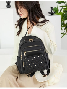 Close-up of black quilted nylon backpack with gold studs and multiple zipper pockets