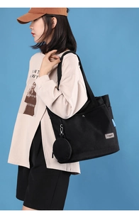 Close-up of black canvas tote bag with a small detachable round coin purse on a model