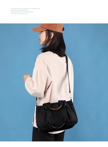 Detail of black nylon crescent bag with brown leather handles and adjustable strap