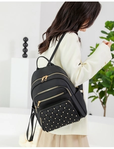 Detail of black oxford backpack featuring gold hardware and studded quilted front pocket