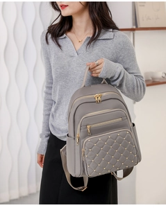 Detail of gray oxford nylon backpack featuring quilted diamond pattern and gold rivets