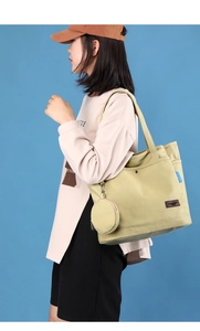 Detail of light yellow canvas tote bag with round coin purse and fashion leather patch