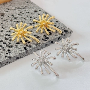 Dettaglio di orecchini a forma di fuochi d'artificio in oro e argento su pietra