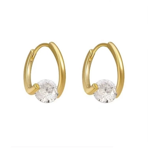 Macro detail of gold C-shaped earrings featuring large round brilliant cut white crystals