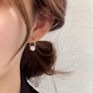 Close-up of a minimalist gold hoop earring featuring a large round clear gemstone on model