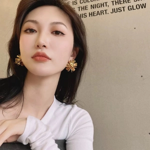 Elegant matte gold multi-layer flower stud earrings worn by an Asian female model