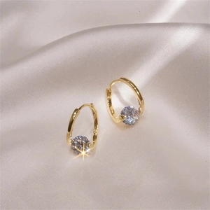 Elegant gold hoop earrings with single large round cubic zirconia on luxury silk fabric
