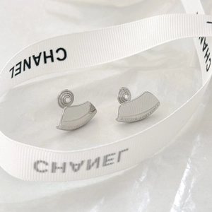 Macro detail of silver-tone curved clip-on earrings with engraved text on white silk