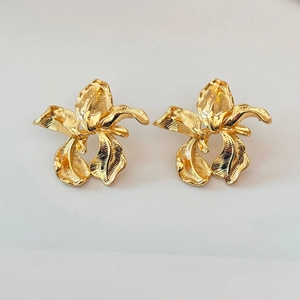 Close-up of golden floral earrings with textured metallic petals and French vintage design