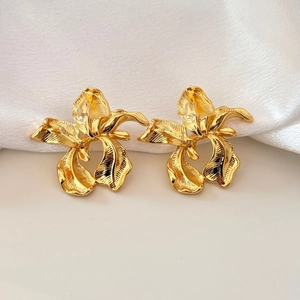 Detail of gold orchid earrings featuring brushed metal texture and floral design