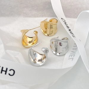 Minimalist irregular wavy gold and silver metal hoop earrings on textured white paper