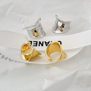 Detail of minimalist wave hoop earrings in polished gold and silver finishes