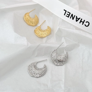 Macro view of C-shaped hammered texture stud earrings in gold and silver finishes