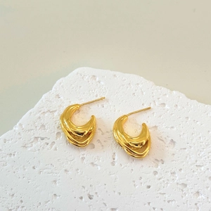 Elegant gold C-shaped layered wire earrings on a white minimalist stone display