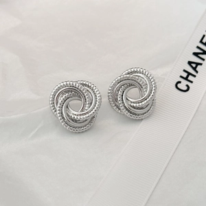 Macro shot of silver S925 interlocking twisted hoop earrings on white silk fabric