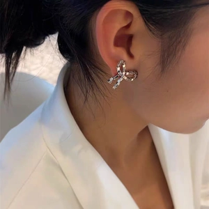 Elegant silver bow stud earrings with geometric metal block design worn by a female model