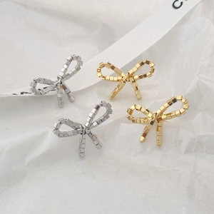 Macro shot of gold and silver bow stud earrings with textured metallic cube beads
