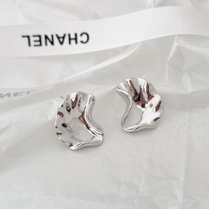 Macro shot of silver liquid metal earrings with irregular wavy edges and mirror finish