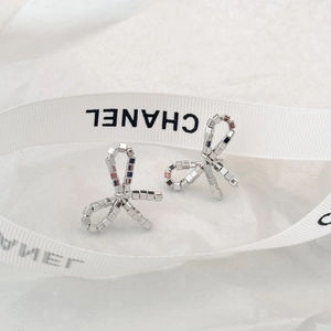 Macro shot of silver bow stud earrings made of tiny metal beads on white silk