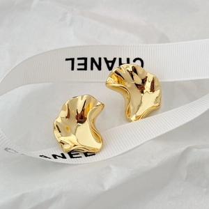 Macro shot of gold irregular wrinkled wave earrings with a high-shine metallic finish