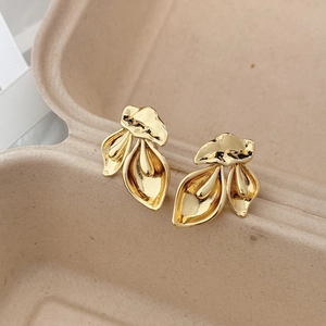 Detailed close-up of golden leaf-shaped earrings with polished fold texture in a gift box