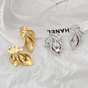 Detailed view of textured metal leaf earrings in gold and silver finishes