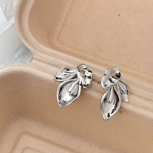 Detailed close-up of polished silver leaf earrings with abstract curved metallic design
