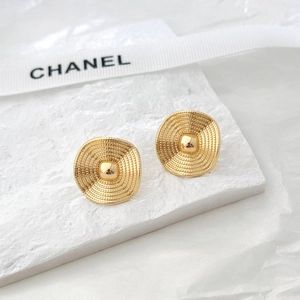 Detail of gold spiral textured oval stud earrings on a textured display plate