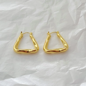 Detailed view of gold irregular hollow triangle geometric hoop earrings on white paper