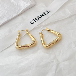 Close-up of golden irregular earrings with molten texture on white silk ribbon