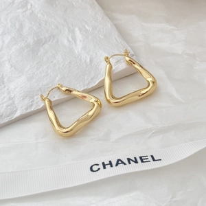 Close-up of golden irregular geometric hollow earrings with textured molten metal finish