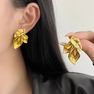 Golden irregular leaf earrings with textured metallic finish on model close-up